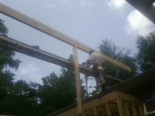 Carpenter setting a ridge beam over a new addition frame — Ice Dam Removal by Roofing Brothers in Harmon