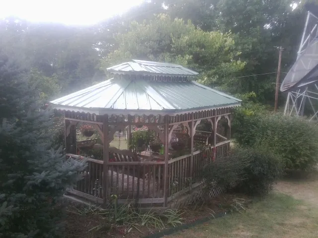 Green metal roof on a backyard gazebo surrounded by garden beds in Harmon