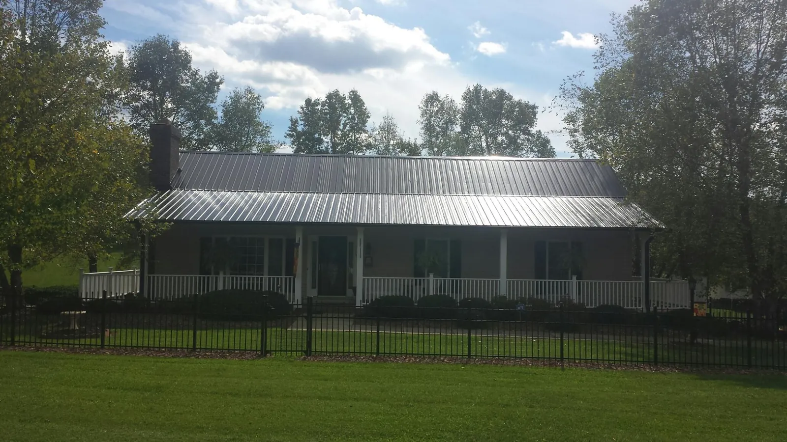 Gray metal roof on a brick ranch with a full width front porch — Gutter Guard Installation work by our crew in Harmon