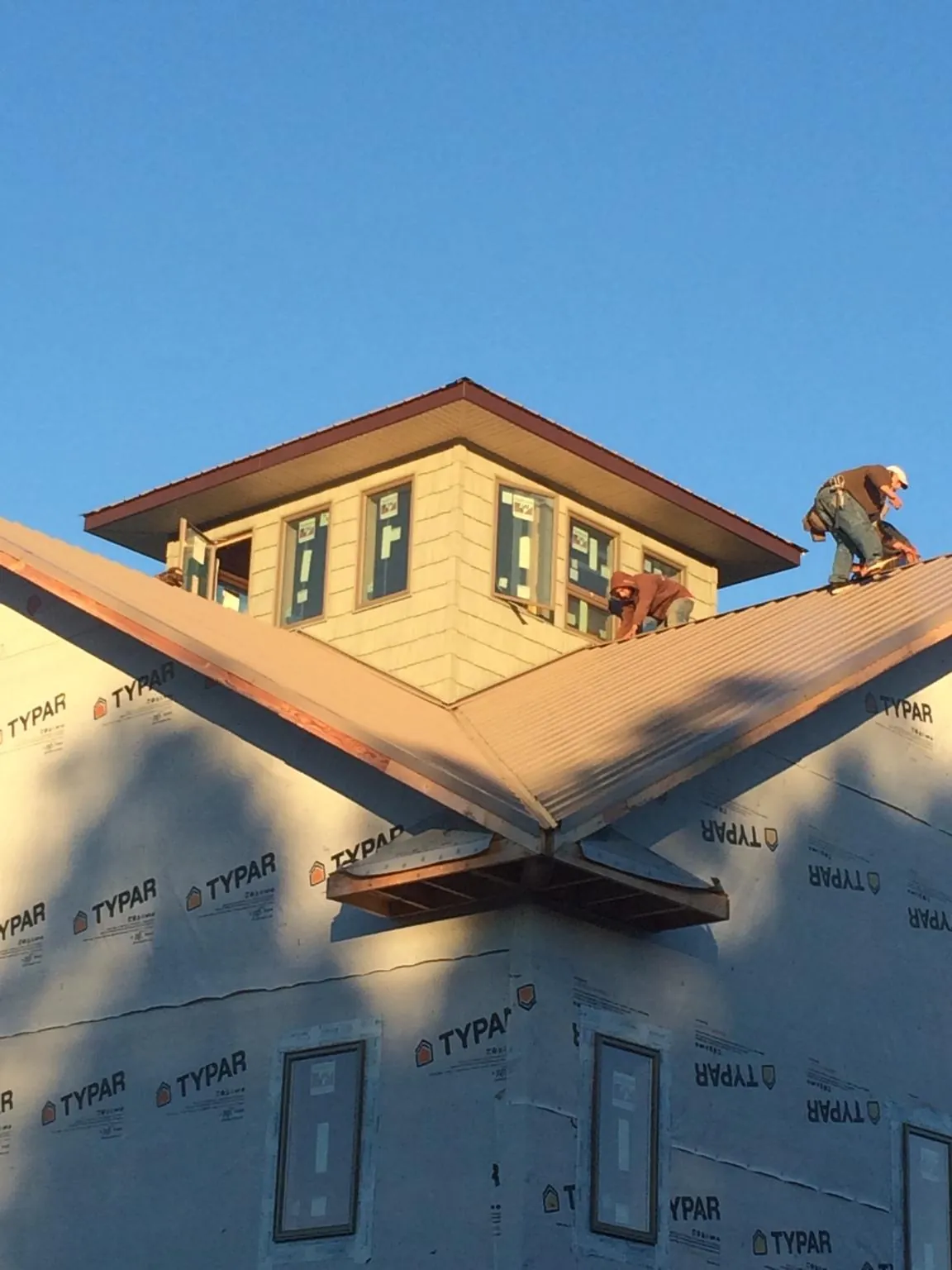 Roofers working around a rooftop cupola on a new metal roof at sunset — Roof Waterproofing in Harmon by Roofing Brothers